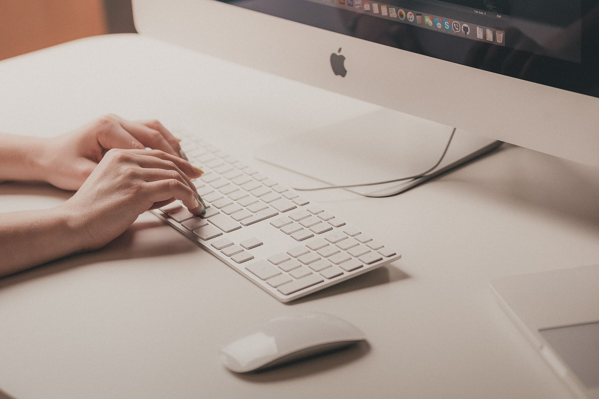 Contacta con nosotros 1 Manos tecleando en teclado blanco de Apple.
